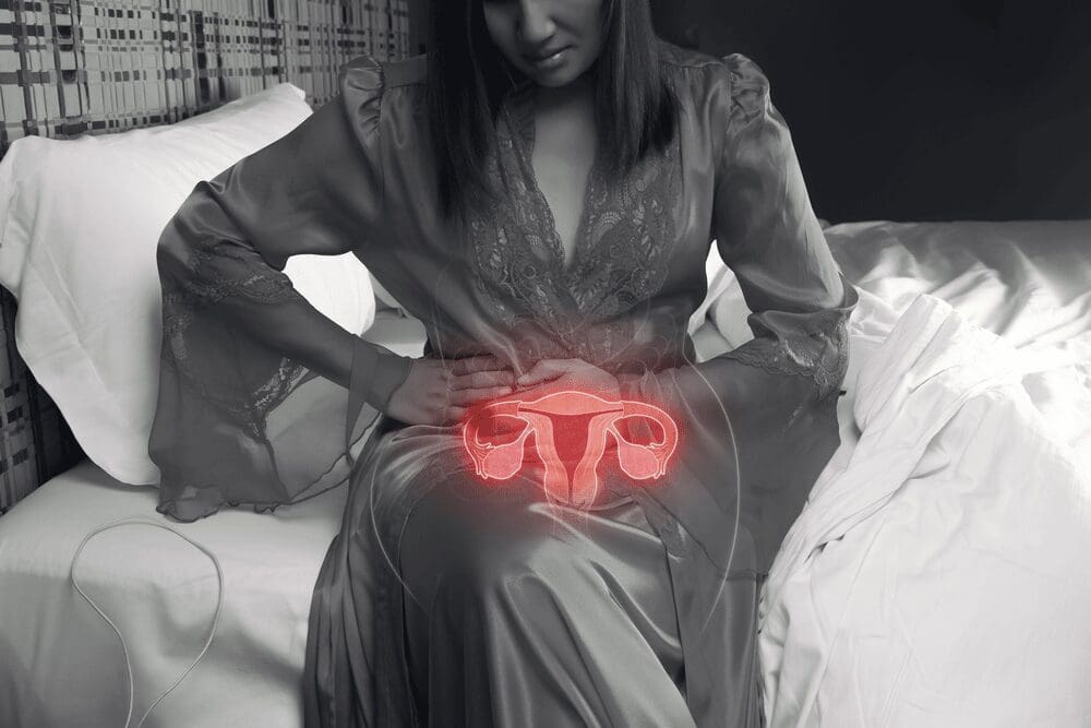 young-female-in-black-and-white-photo-holding-stomach-with-animated-uterus-shining-through