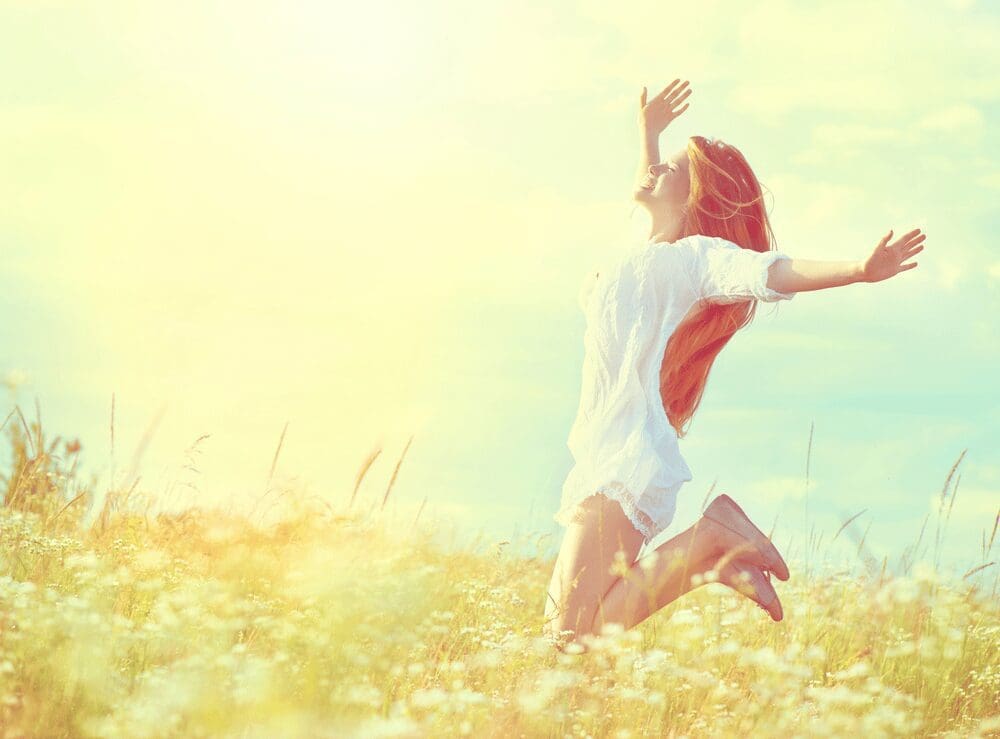 young-woman-jumping-with-her-hands-out-in-a-field